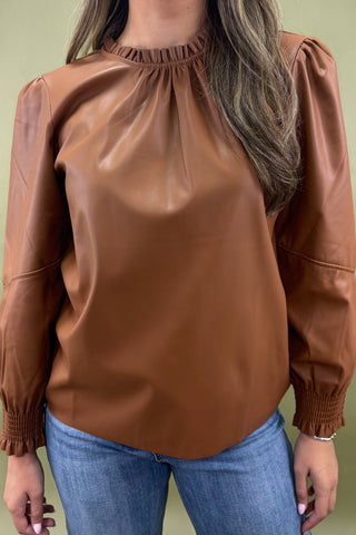 Brown leather blouse worn by a person against a green background