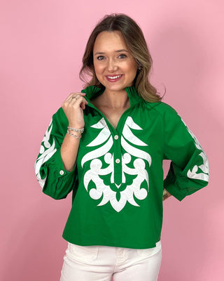 Woman wearing a green shirt with white patterns against a pink background