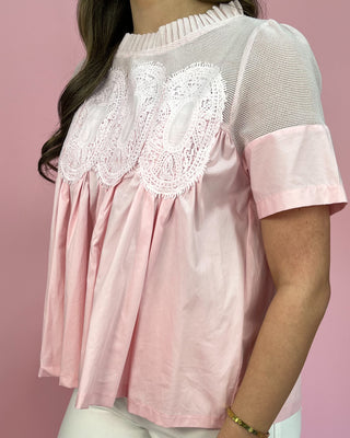 Pink blouse with lace details on a pink background