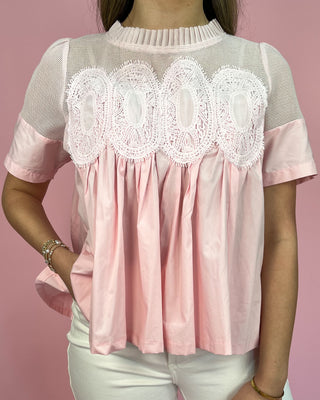 Pink blouse with lace details on a pink background