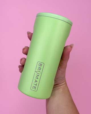 Green tumbler held in a hand against a pink background