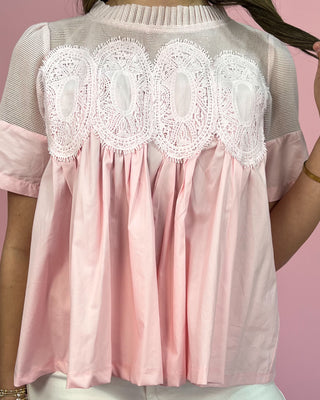 Pink blouse with lace details on a pink background