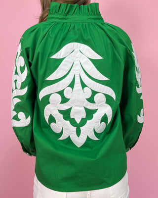 Green jacket with white intricate design on a pink background