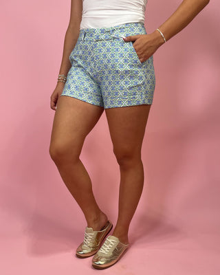 Person wearing blue patterned shorts on a pink background