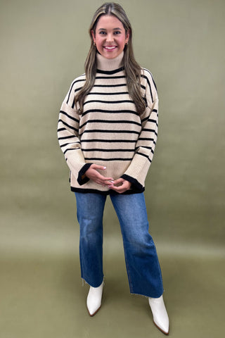 Woman wearing a striped sweater and blue jeans against a plain background