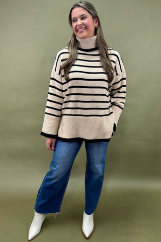 Woman wearing a striped sweater and blue jeans against a green background