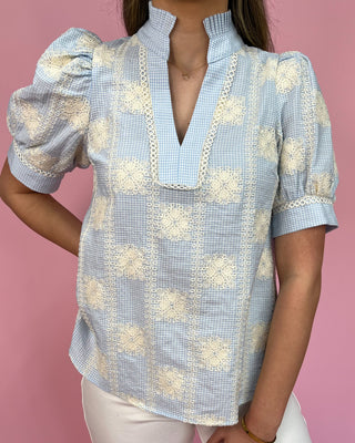 Woman wearing a blue and white floral blouse against a pink background