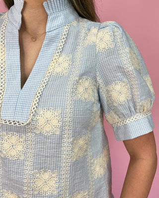 Light blue checkered blouse with white lace details on a pink background