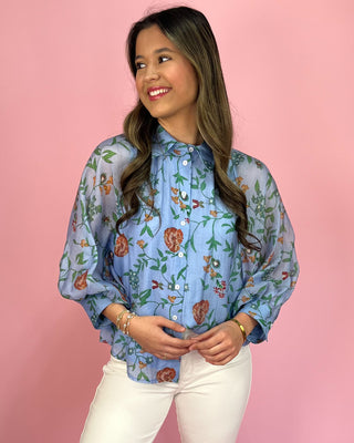 Woman wearing a floral blouse against a pink background