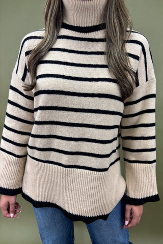 Person wearing a cream and black striped sweater against a green background