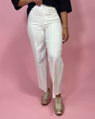 Person wearing white pants and gold shoes on a pink background