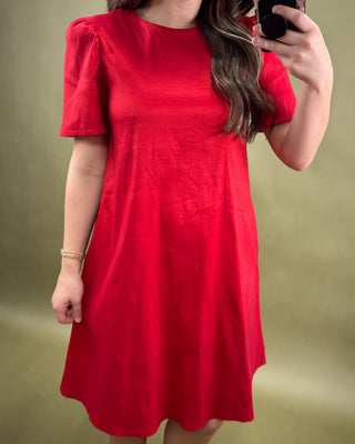 Person wearing a red dress against a green background