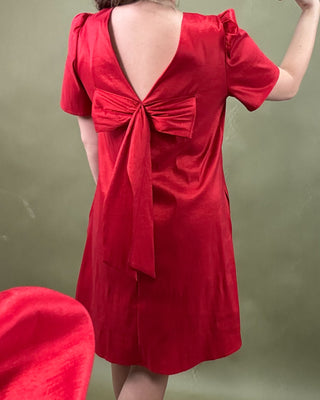 Red dress with a bow detail on the back against a green background