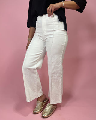 Person wearing white pants and gold shoes on a pink background