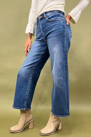 Person wearing blue jeans and white boots on a green background