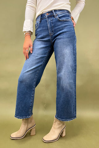 Person wearing blue jeans and beige boots on a green background