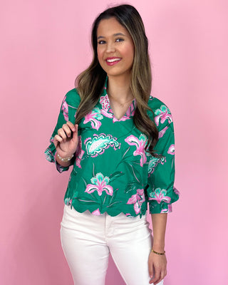 Woman wearing a green floral blouse against a pink background