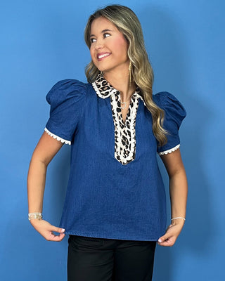 Blue denim puff sleeve top with leopard print collar and neckline trim, white scalloped accents, and a relaxed fit.
