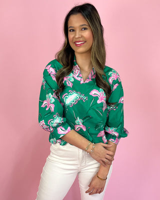 Woman wearing a green floral blouse against a pink background