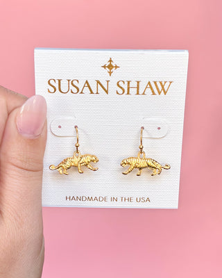 Gold tiger-shaped earrings on a Susan Shaw branded card against a pink background
