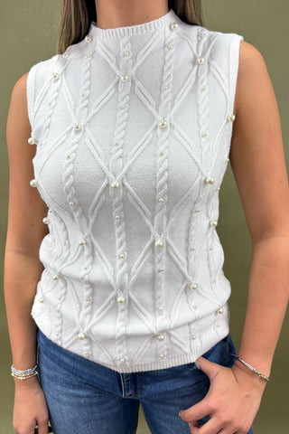 White knitted vest with pearl embellishments worn by a person against a neutral background