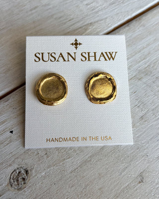 Gold earrings on a Susan Shaw branded card on a wooden surface