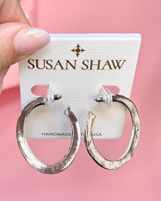 Silver hoop earrings on a Susan Shaw branded card against a pink background