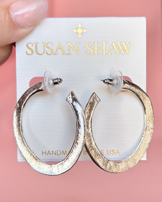 Gold hoop earrings on a Susan Shaw branded card against a pink background