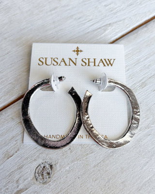 Silver hoop earrings on a Susan Shaw branded card with a wooden surface background