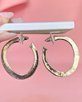 Gold hoop earrings on a pink background