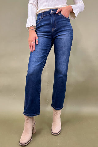 Person wearing blue jeans and beige boots on a plain background