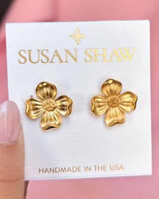 Gold flower-shaped earrings on a Susan Shaw branded card with a pink background