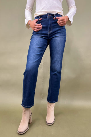 Person wearing blue jeans and white boots on a plain background