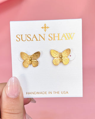 Gold butterfly earrings on a Susan Shaw branded card with a pink background