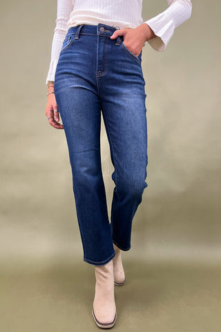 Person wearing blue jeans and a white top on a beige background