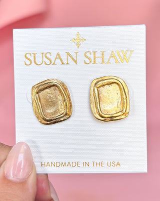 Gold earrings on a Susan Shaw branded card with a pink background