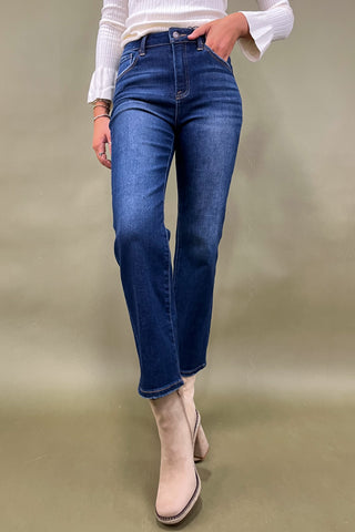 Person wearing blue jeans and beige boots on a plain background