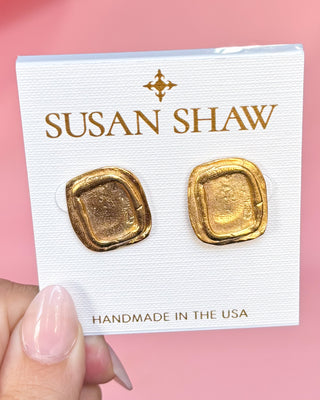Gold earrings on a Susan Shaw branded card against a pink background