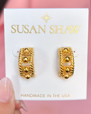 Gold earrings on a Susan Shaw branded card with a pink background