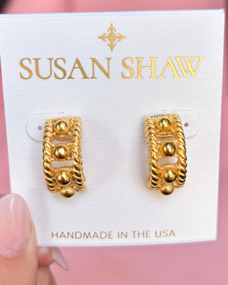 Gold earrings on a Susan Shaw branded card with a pink background
