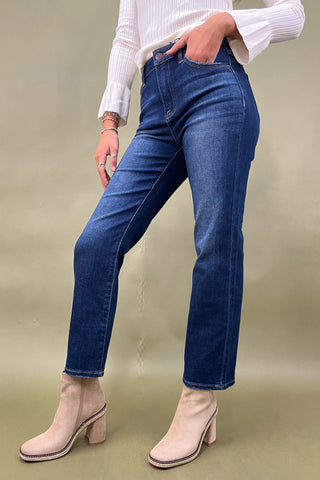 Person wearing blue jeans and beige ankle boots on a plain background