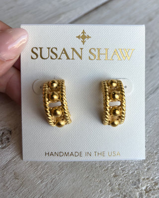 Gold earrings on a Susan Shaw branded card with a hand holding the card.