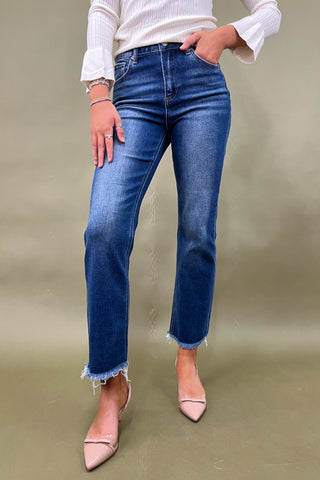 Person wearing blue jeans and a white top on a beige background