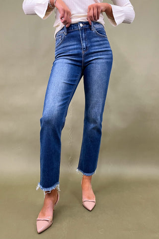 Person wearing blue jeans and a white top on a plain background