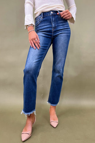 Person wearing blue jeans and a white top on a plain background