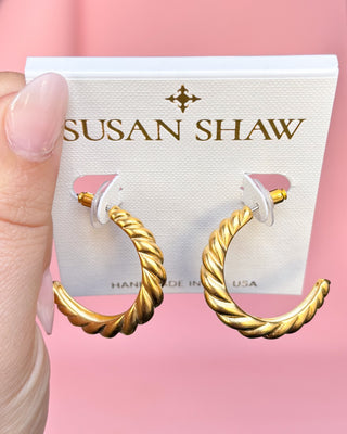 Gold hoop earrings held against a pink background with 'Susan Shaw' branding.