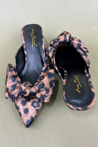 Pair of leopard print shoes with a bow on a light green background