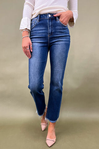 Person wearing blue jeans and a white top on a beige background