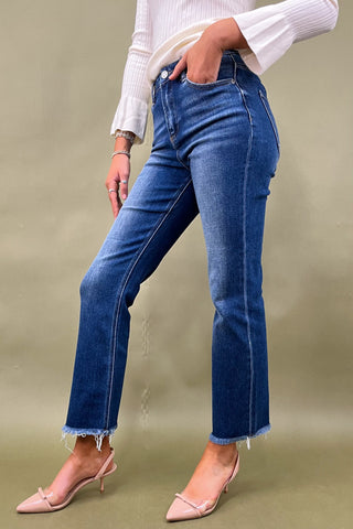 Person wearing blue jeans and a white top on a plain background