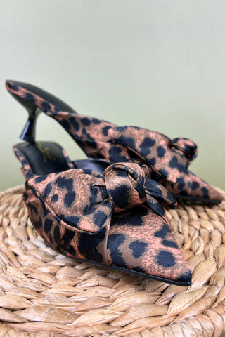Leopard print high-heeled shoes with bows on a woven surface